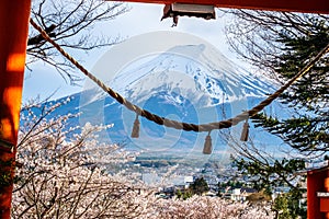 Fuji mountain from stair way at Chureito Red Pagoda Fujiyoshida, shimenawa enclosing rope leaning of cityscape view with pink full