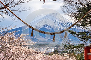 Fuji mountain from stair way at Chureito Red Pagoda Fujiyoshida,shimenawa enclosing rope leaning of cityscape view with pink full