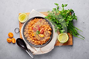 Ful Medames or Fava Beans in black bowl at grey backdrop. Foul Mudammas is a Egyptiancuisine breakfast dish