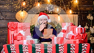 Fulfill cherished dreams. Happy winter holidays. Man bearded santa claus hat reading letters. Hipster prepared gifts for