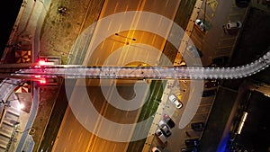 Full aerial time lapse view of night flowing traffic and people using overpass