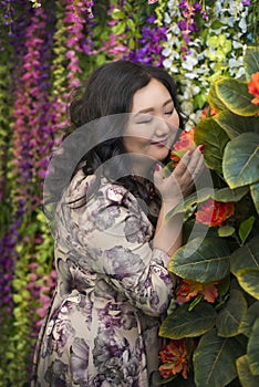 Full Asian woman in the room with flowers.