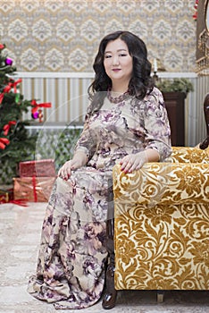 A full Asian woman sitting on a chair in the living room.