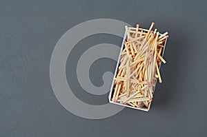 Full big cardboard matchbox of many matchsticks with red sulfur on dark concrete table on kitchen