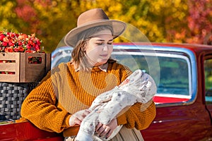 A full-bodied mother with a newborn little daughter stands near a red retro car loaded