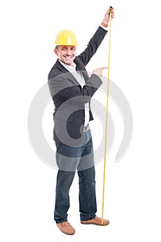 Full body of architect wearing hardhat pointing measuring tape