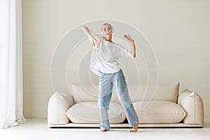 Beautiful woman meloman with very short hair dancing near couch photo
