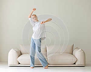 Beautiful woman meloman with very short hair dancing near couch photo