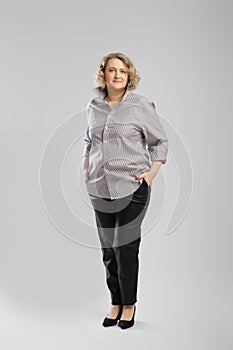 Full body casual studio portrait of senior woman in grey shirt and trousers