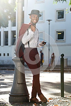 Full body cool african american fashion model with vintage suit posing with mobile phone in city