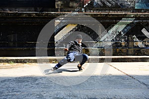 Full body of energetic street dancer dancing on city street during sunny day