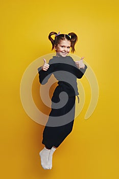 Full body girl smiling and showing thumbs up with both hands while jumping