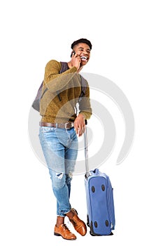 Full body handsome young african american man standing with luggage and talking with mobile phone against isolated white