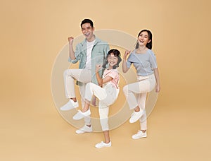 Full body happy fun Asian family doing winner gesture celebrate clenching fists raise up leg isolated on color background