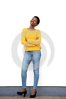 Full body happy young african american woman standing against white wall and looking up