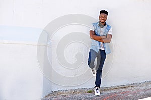 Full body happy young man leaning against wall with headphones