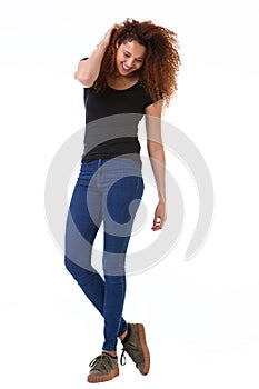 Full body happy young woman with hand in curly hair standing against isolated white background photo