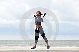 Full body healthy african american woman relaxing with hands behind head at beach