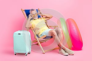 Full body length cadre of retired man lying sunbed mallorca country sunny weather touch his glasses isolated on pink