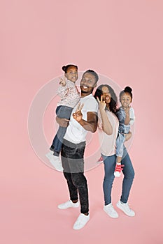 Full body length of excited african american man, woman and two girls laughing and posing