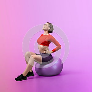 Full body length gaiety shot athletic and sporty young woman with fitness ball