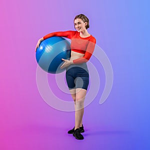 Full body length gaiety shot athletic and sporty young woman with fitness ball