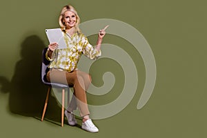 Full body length photo of senior woman sitting stool with tablet direct finger website job list offers isolated on khaki