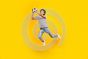 Full body length photo of young professional sportsman goalkeeper catch ball playing soccer jumping isolated on yellow
