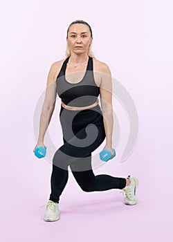 Full body length shot active and sporty senior woman lifting dumbbell. Clout