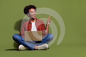 Full body photo of attractive young man laptop sit floor point empty space dressed stylish brown clothes isolated on