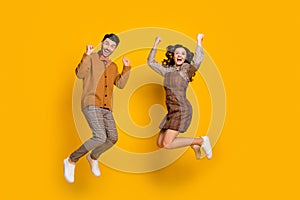 Full body photo of brown haired man and woman excited winner raise fists success jump isolated on yellow color