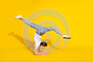 Full body photo of charming happy young woman stand hands upside-down stretch isolated on yellow color background