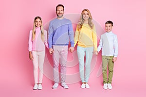 Full body photo of cheerful family mom dad little kids hold hands isolated over pastel color background
