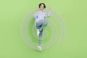 Full body photo of cheerful young joyful nice happy woman jump up winner cool isolated on green color background