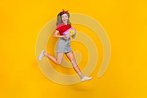 Full body photo of cool little girl run birthday wear t-shirt hairband skirt sneakers isolated on yellow background