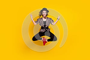 Full body photo of crazy young woman jump up stick out tongue make rock sings isolated on yellow color background
