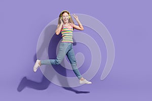 Full body photo of cute teen blonde woman running jumping v-sign dressed stylish striped clothes  on violet