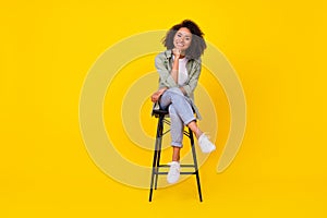 Full body photo of cute young girl wavy hair sit stool smiling banner dressed stylish khaki clothes  on yellow