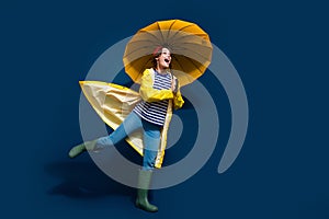 Full body photo of funky carefree girl bring umbrella running wear yellow rain jacket goretex walk puddle isolated on photo