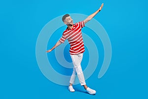 Full body photo of funky happy cheerful man look empty space hands wings isolated on blue color background