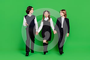 Full body photo of funny small girl boys hold hands go wear school uniform isolated on green background