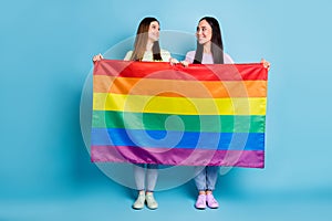 Full body photo of funny tricky lesbians couple visit foreign parade support same sex marriages hold gay rainbow flag