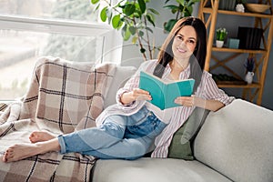 Full body photo of gorgeous positive lady sitting couch hands hold opened book sunlight window morning house inside