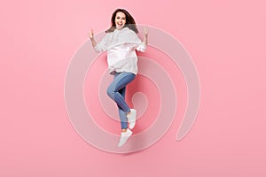 Full body photo of happy nice cheerful woman jump air make fingers thumbs up isolated on pink color background