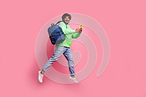 Full body photo of jumping happy student guy with rucksack behind using phone order pizza after lecture isolated on pink