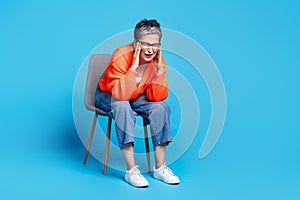 Full body photo of lovely senior lady sit chair migraine suffer dressed stylish orange garment isolated on blue color