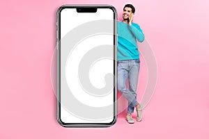 Full body photo of nice young man lean on vertical banner talk phone dressed stylish blue garment isolated on pink color