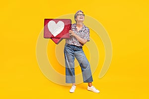 Full body photo of pensioner woman heart icon look empty space dressed stylish leopard print clothes isolated on yellow