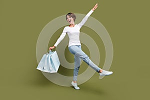 Full body photo of pretty young girl have fun happy walking shopping bags wear trendy white outfit isolated on khaki
