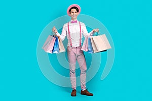 Full body photo of satisfied nice guy wear white shirt pink headwear bow tie holding shopping bags isolated on blue
